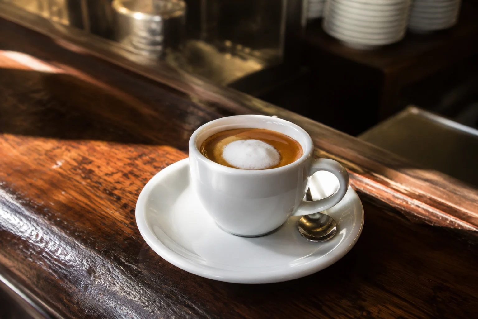 Tasse de caffè macchiato avec mousse de lait légèrement versée sur un espresso