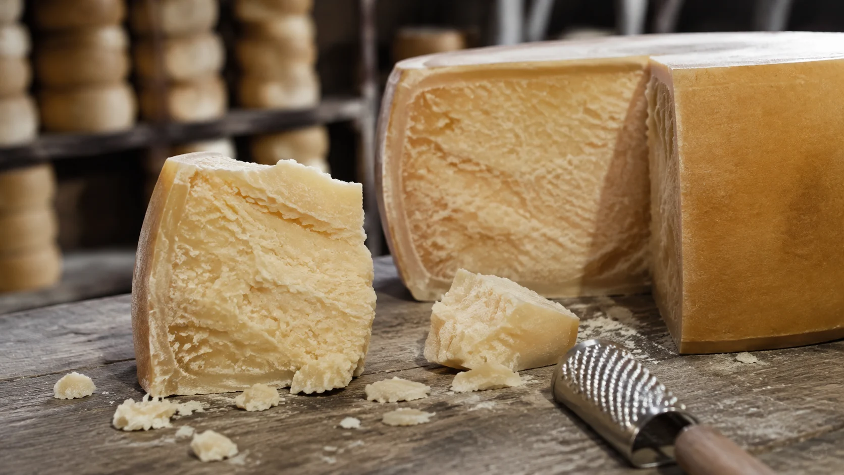 Meule de Grana Padano et copeaux de fromage sur planche en bois
