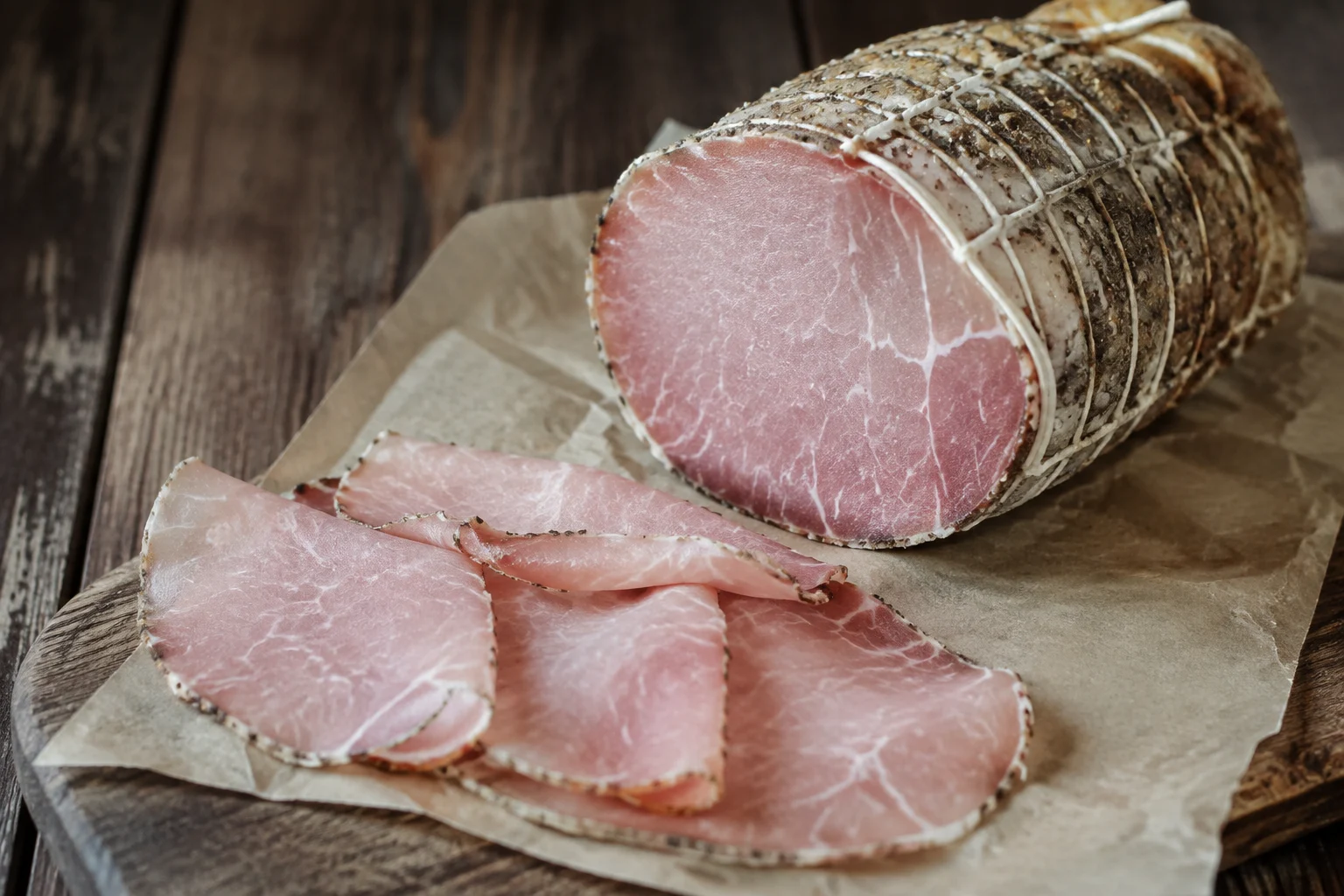 Fines tranches de lonza italienne sur planche en bois, charcuterie délicate et maigre
